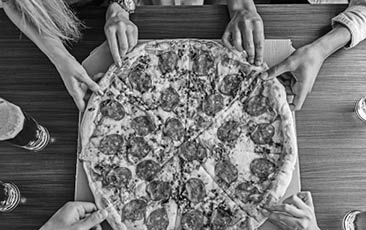 High angle shot of a group of unrecognizable people's hands each grabbing a slice of pizza