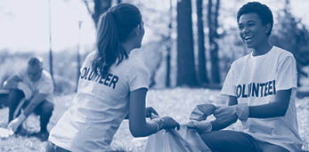 Green volunteering. Optimistic two volunteers holding garbage bag and communicating