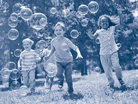 Multi-ethnic group of little friends with toothy smiles on their faces enjoying warm sunny day while participating in soap bubbles show