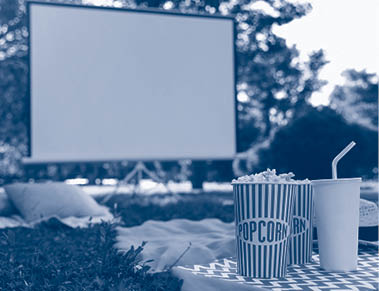 Popcorn and drink on green grass in open air cinema. Space for text