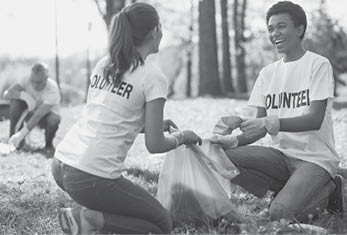 Green volunteering. Optimistic two volunteers holding garbage bag and communicating