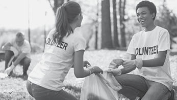 Green volunteering. Optimistic two volunteers holding garbage bag and communicating