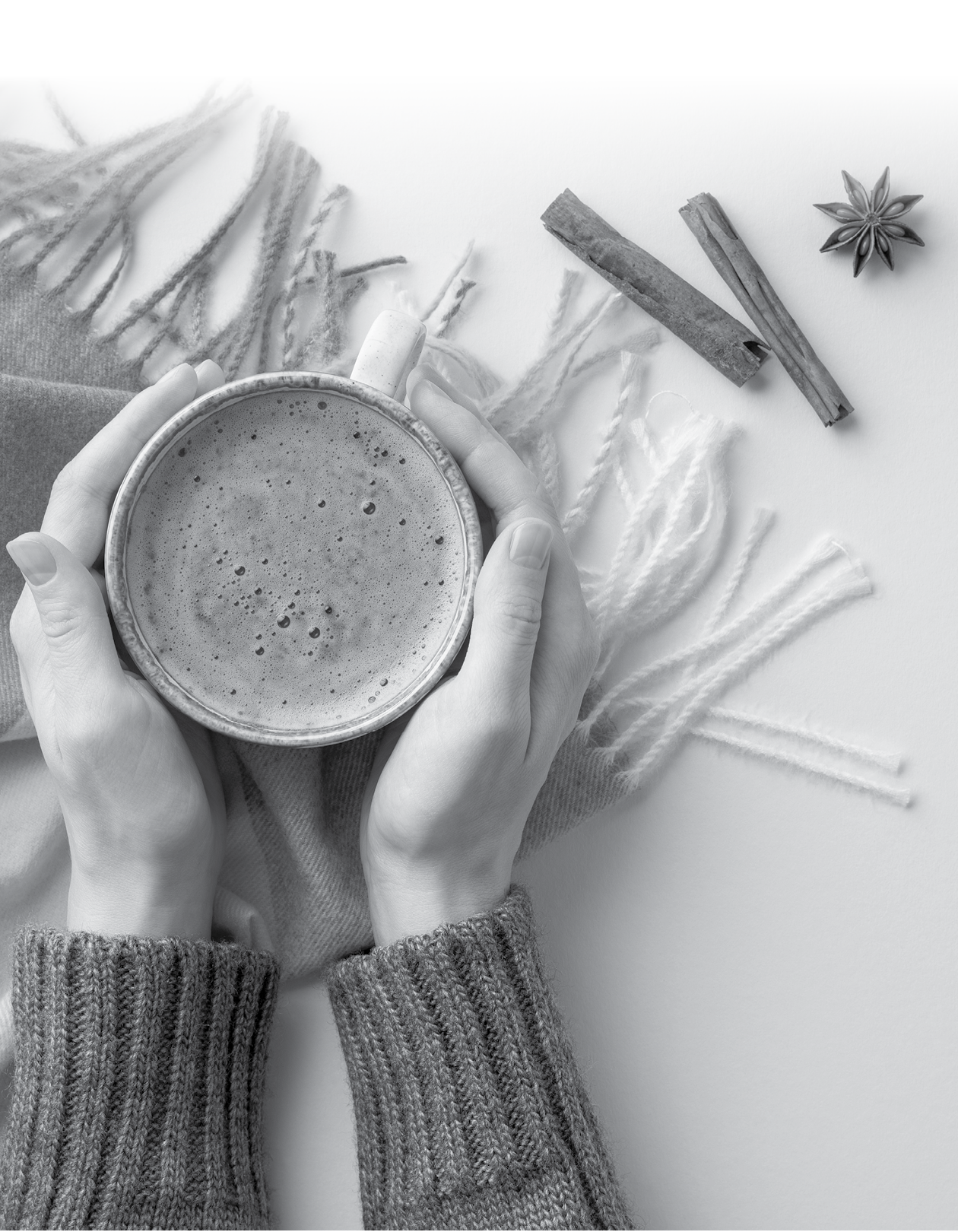 Autumn concept. First person top view photo of young woman's hands in pullover holding mug of hot drinking over plaid scarf cinnamon sticks anise and yellow maple leaves on isolated beige background