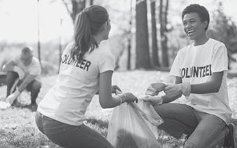 Green volunteering. Optimistic two volunteers holding garbage bag and communicating