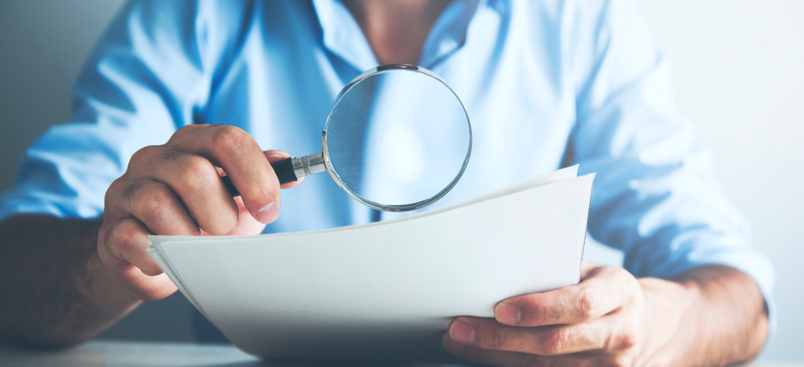 Person viewing documents through magnifying glass